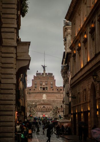 Scenic view of Castel Sant'Angelo from a bustling Roman street, capturing urban life.